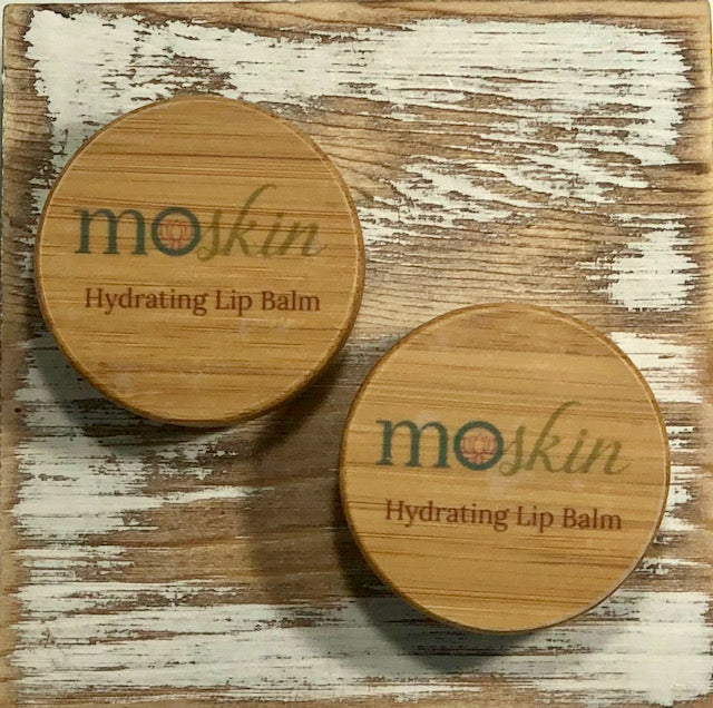 A close-up of moisturized lips being prepped with a fingertip applying a thin layer of balm before lipstick.