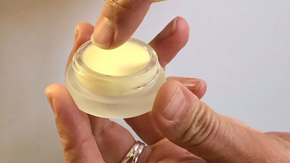 A hand pressing a few drops of face oil into freshly misted skin beside a broad‑spectrum SPF, in soft morning light.