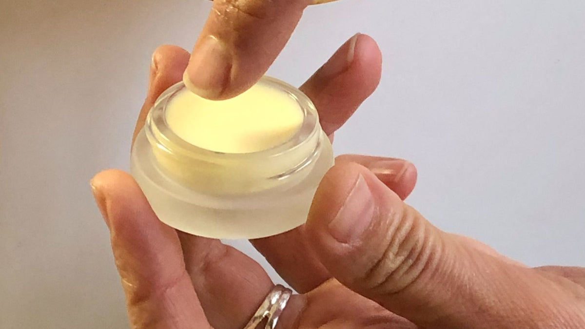 A hand pressing a few drops of face oil into freshly misted skin beside a broad‑spectrum SPF, in soft morning light.